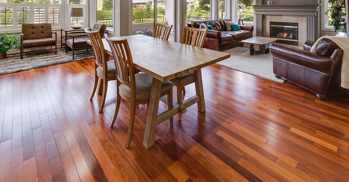 Natural wood flooring in a dining area with leather couches in the background